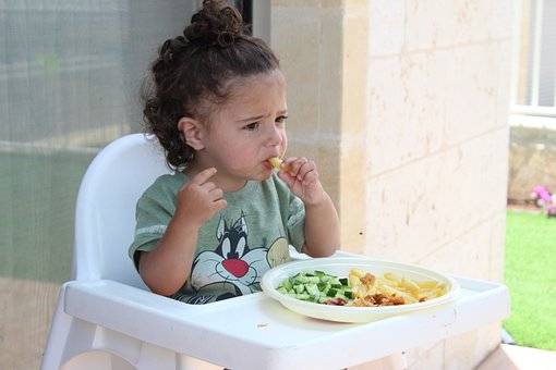 A child having her meal, not sure whether she is enjoying!